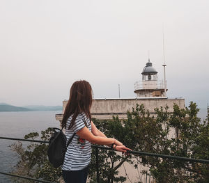 Rear view of woman standing by sea against sky