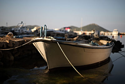 Close-up of fishing boats moored at shore against clear sky