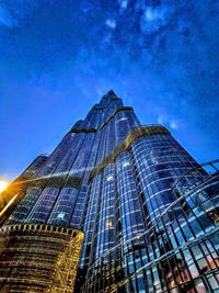 Low angle view of modern glass building against blue sky