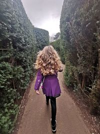 Rear view of woman walking on road against mountain