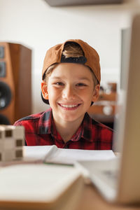 Happy little boy enjoying during home schooling in the living room and looking at camera.