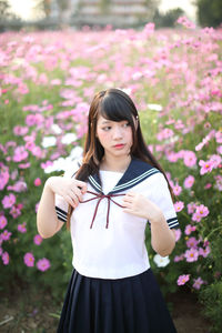 Young woman looking away while standing against flowering field