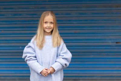 Portrait of young woman standing against wall