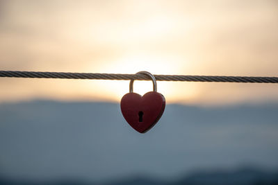 Close-up of padlocks hanging on rope against sky