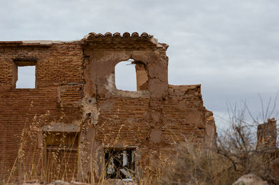 Low angle view of old ruin building against cloudy sky