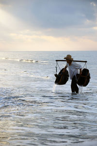 Man standing on beach against sky during sunset