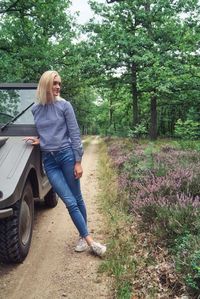 Full length of woman standing on land by car and plants