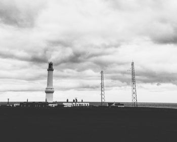 Lighthouse on coast against cloudy sky