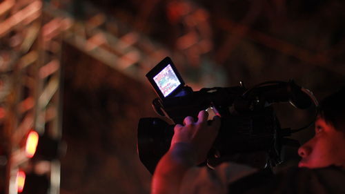 Low angle view of man filming with movie camera at night