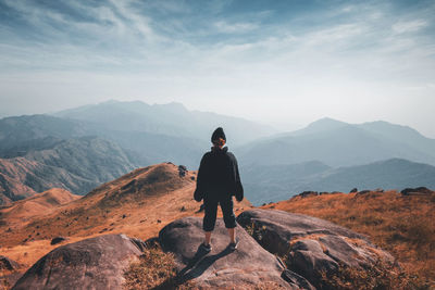 Rear view of man standing on mountain against sky