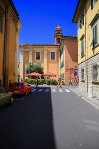 Street amidst buildings against blue sky