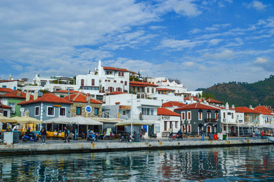 Buildings by river against sky in town