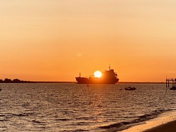 Silhouette ship in sea against sky during sunset