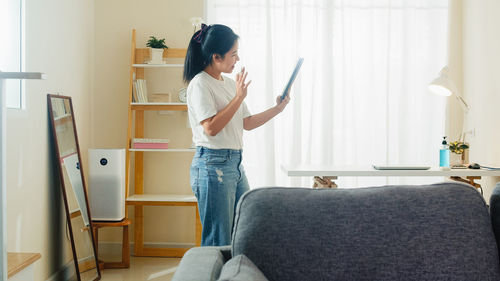 Side view of woman standing on sofa at home