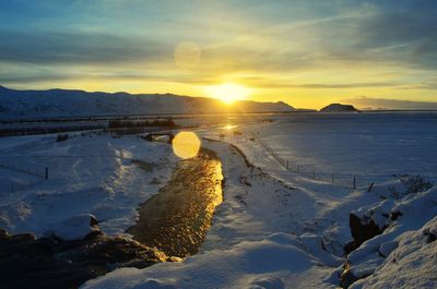 Scenic view of frozen lake against sky during sunset