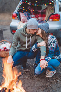 Smiling couple embracing while sitting by trunk