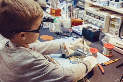 Rear view of boy sitting on table