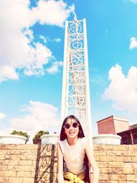 Portrait of smiling young woman standing against sky