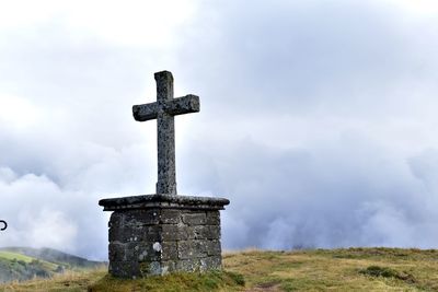 Cross on field against sky