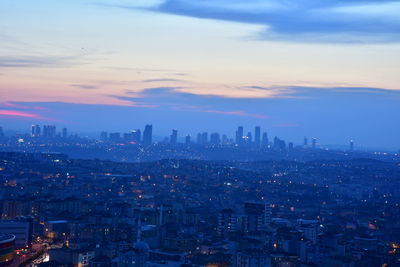 Illuminated cityscape against sky during sunset