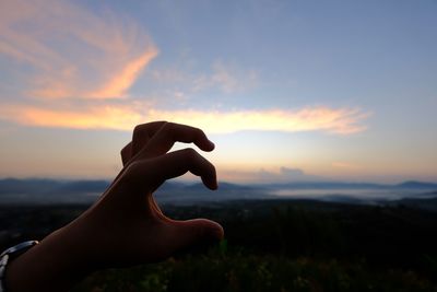 Silhouette hand gesturing against sky during sunset