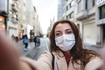 Portrait of woman wearing mask standing on city street