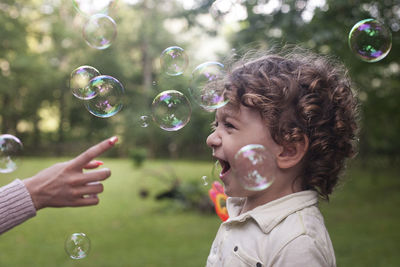 Boy playing with bubbles at park