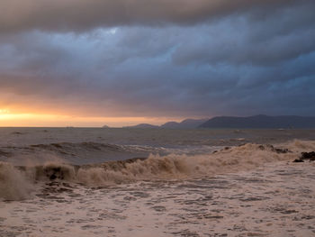 Scenic view of beach against dramatic sky