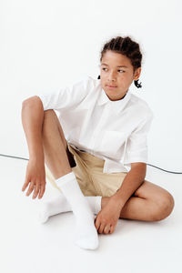 Portrait of young woman sitting against white background