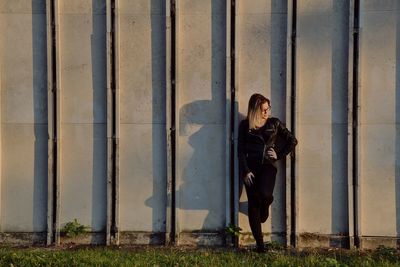 Full length of woman standing against wall