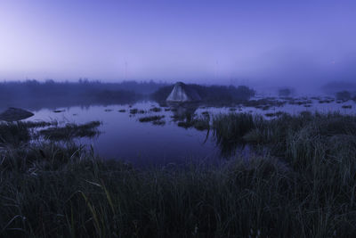 Scenic view of foggy pond at dawn with windmills on horizon