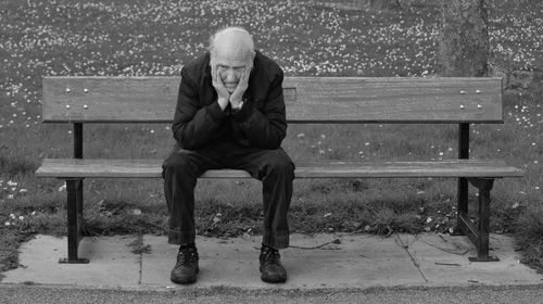 Full length of senior man sitting on bench in park