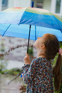 Rear view of woman holding umbrella