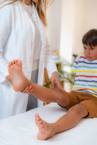 Pediatric doctor doing medical exam with boy on bed.