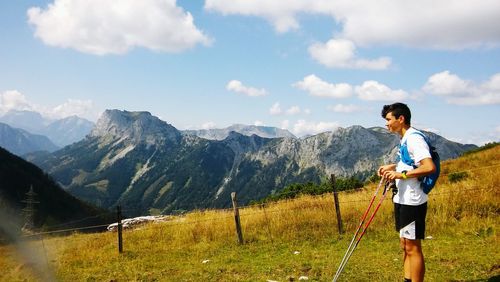 Side view of teenage boy standing on mountain against sky