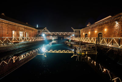 Illuminated bridge over river at night