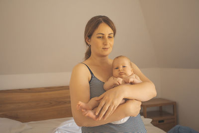 Portrait of young woman sitting on bed at home