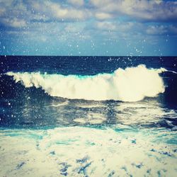 Waves splashing on sea against sky