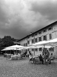 People sitting on table by buildings against sky