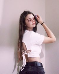 Beautiful young woman standing against wall