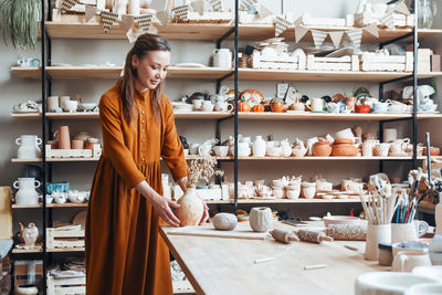 Handmade craft, woman with earthenware in pottery shop