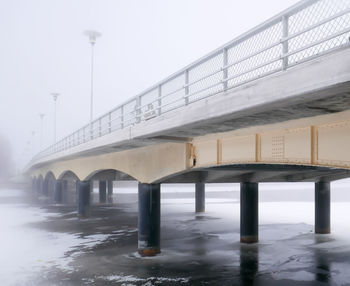 Low angle view of bridge over sea against sky during winter