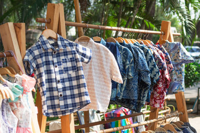 Wooden clothes racks with colorful short sleeve shirts on hangers. clothes on street market.