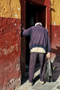 Rear view of woman standing against wall