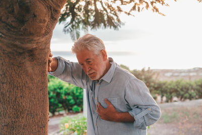 Portrait of senior man standing against trees