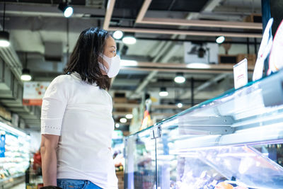 Young asian woman kid with face mask in supermarket. concept for life in outbreak and new normal.