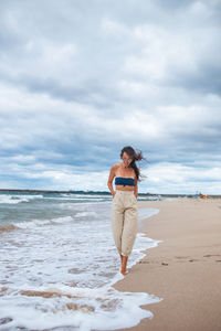 Full length of woman walking on beach against sky