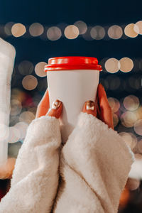 Female hands holding a plastic cup with hot tea or coffee. christmas holiday