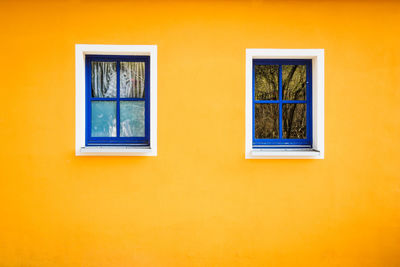 Close-up of blue windows on orange wall of building