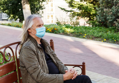 Portrait of woman sitting on seat in city